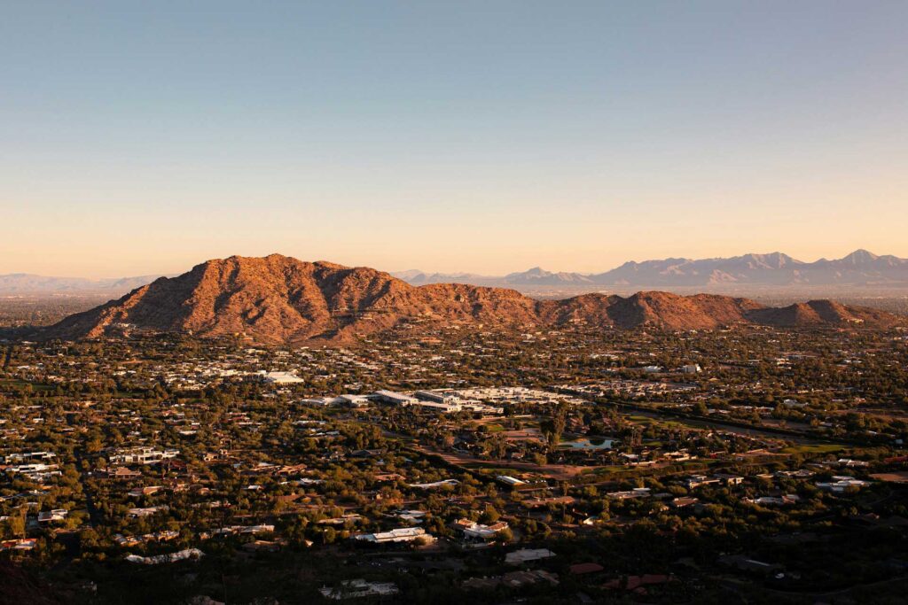 A panoramic view of mountains and a suburban landscape at sunset.