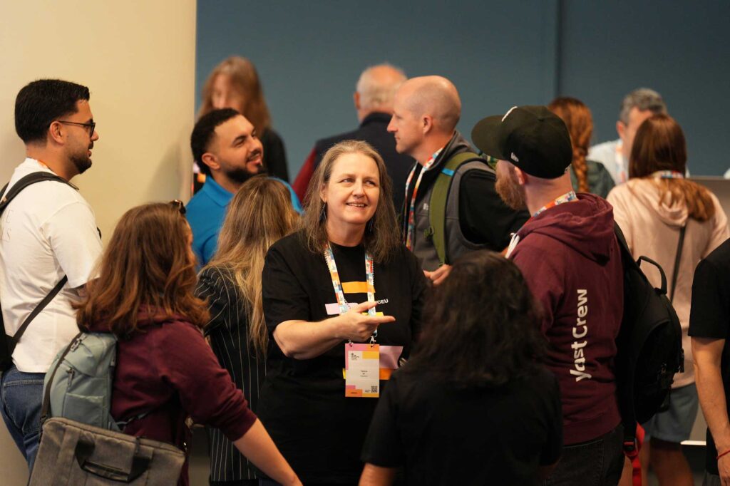 A group of people chatting and networking at an event, with one person gesturing.